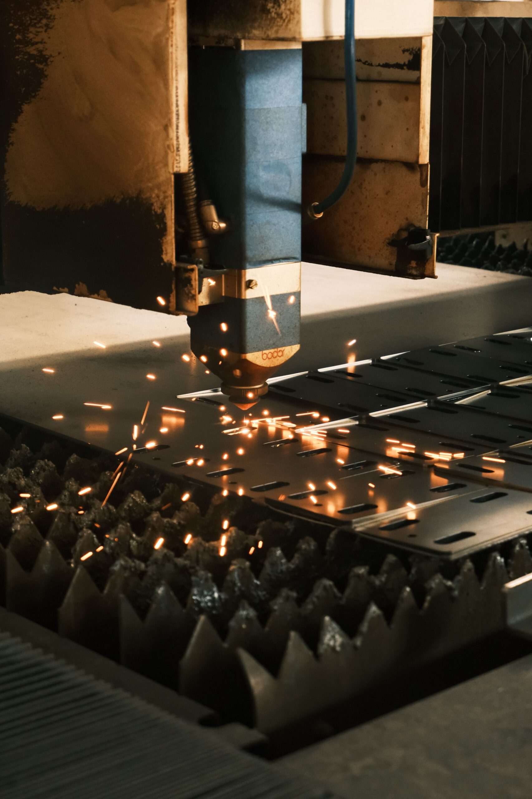 Close-up of a laser cutter in action, producing sparks in a modern manufacturing facility.